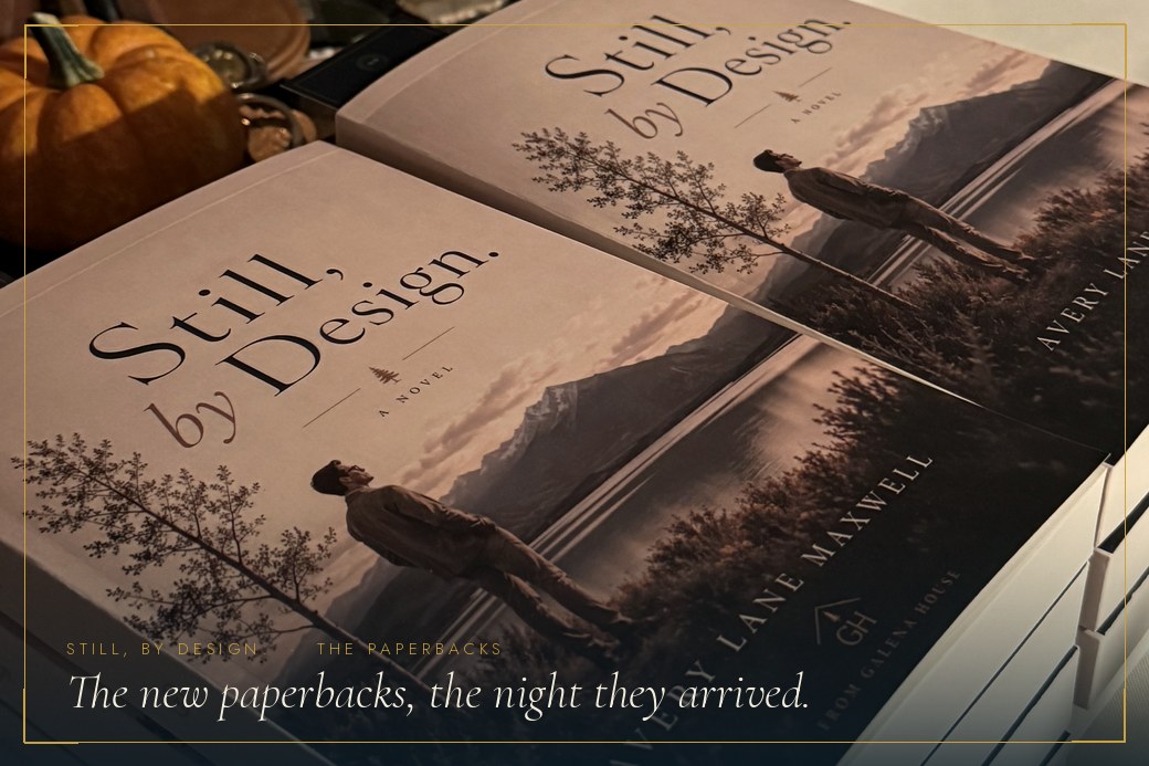 The trade paperbacks of Still, by Design., stacked on a table with small pumpkins
